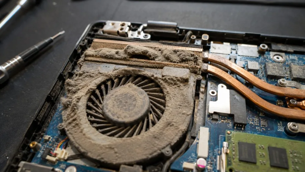 Interior de un portátil con el ventilador y el disipador llenos de polvo, causa del ruido y el calor